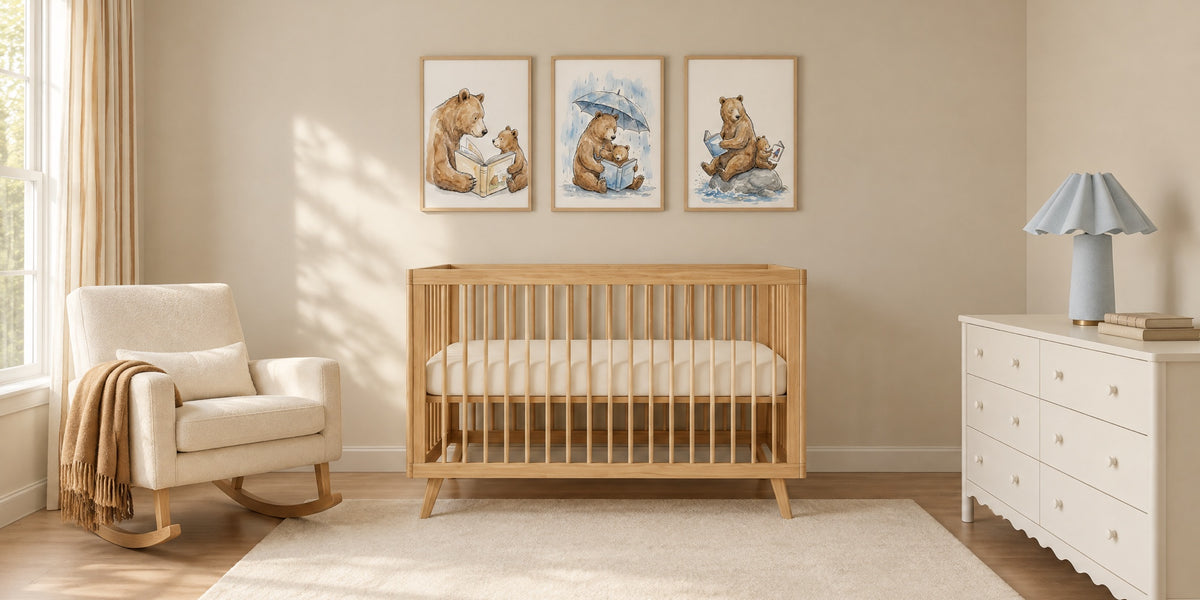 Bear nursery: a honey pine crib under three framed watercolor-style prints of bears reading with their cubs, an ivory rocker and a white dresser with a blue lamp
