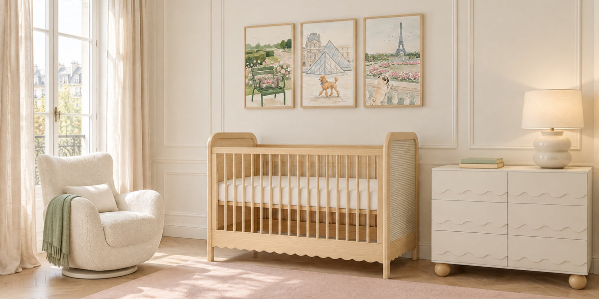 Paris themed nursery: oak cane crib under three framed watercolor-style Paris animal prints, with a blush rug, ivory glider and wave-front white dresser