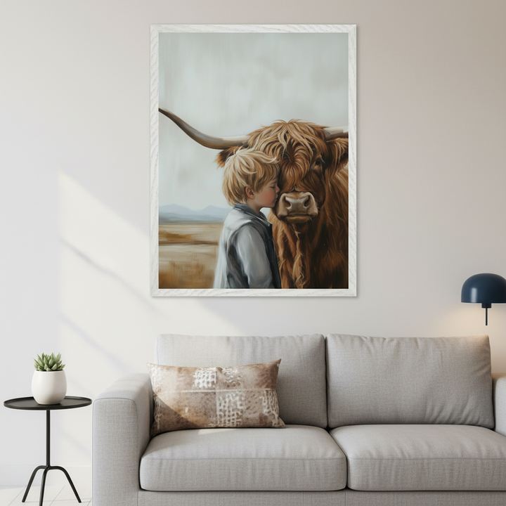 Modern living room with a light grey sofa and black side table. A large framed painting of a blond boy kissing a brown Highland cow in a field hangs centered above the sofa. The artwork has a soft, painterly style.