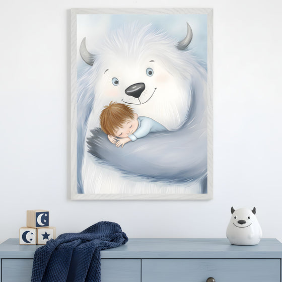 A framed illustration of a fluffy, friendly white yeti cradling a sleeping child in its furry arms, both with peaceful expressions. The artwork hangs above a light blue dresser decorated with a navy knit blanket, moon-and-star wooden blocks, and a small yeti-themed figurine.