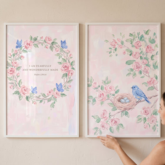 Airy watercolor pink garden wall art set of 2 with pink roses, butterflies, scripture text, and a blue bird by a nest.