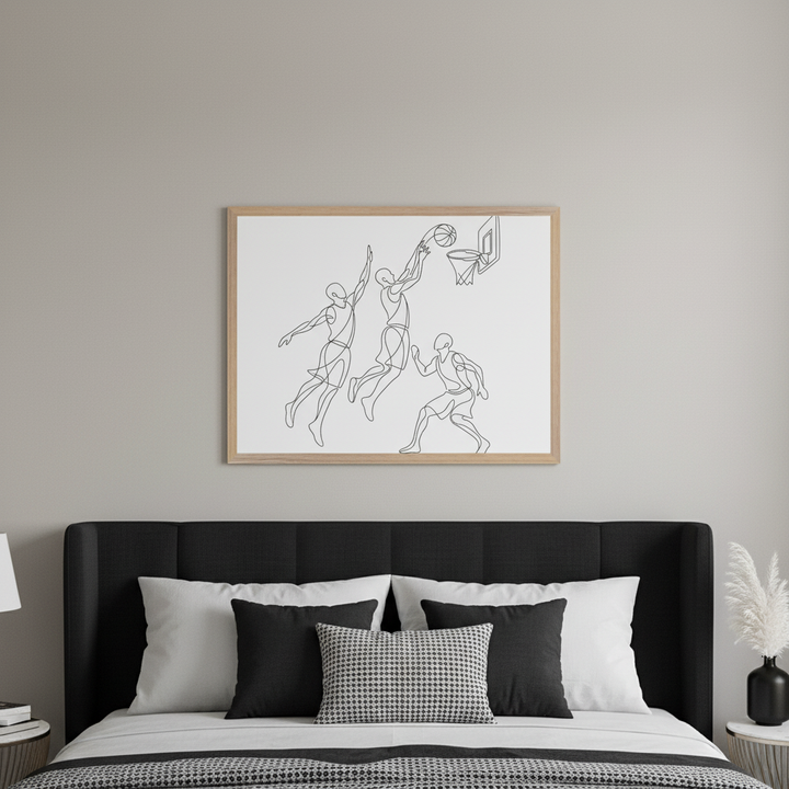 Modern bedroom with a black upholstered bed and white and black pillows. A framed line art print of three basketball players, one shooting into a hoop, hangs centered above the bed.