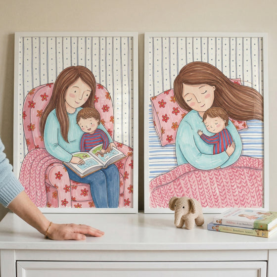 This image features two framed illustrations side-by-side on a white surface, depicting tender moments between a mother and her young child.
The illustration on the left shows a woman with long brown hair wearing a light blue long-sleeved shirt and blue pants. She is sitting in a large pink armchair adorned with a red floral pattern. A small child with short brown hair, dressed in a red and blue striped shirt, sits on her lap. Together, they are engaged in reading a book, which they both hold open.
