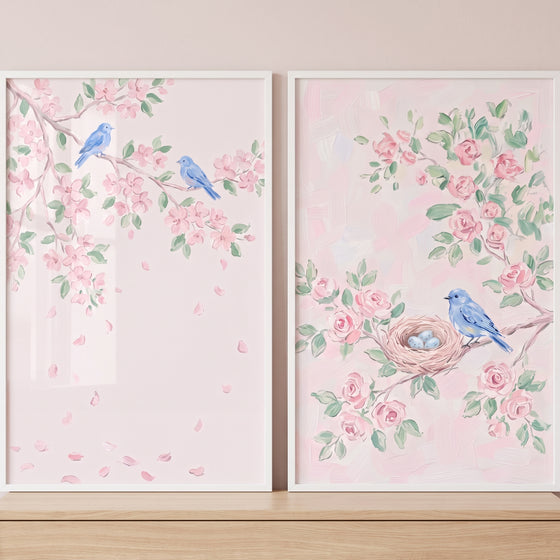 Blossom branch blue bird wall art set of 2 shows bluebirds, a nest with eggs, and pink flowers in white frames.
