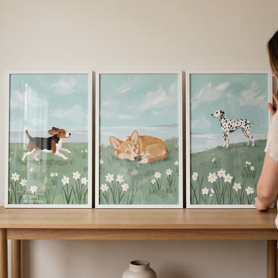 Beagle, corgi, and dalmatian prints in this blue sky coastal dogs wall art set of 3 with white flowers.
