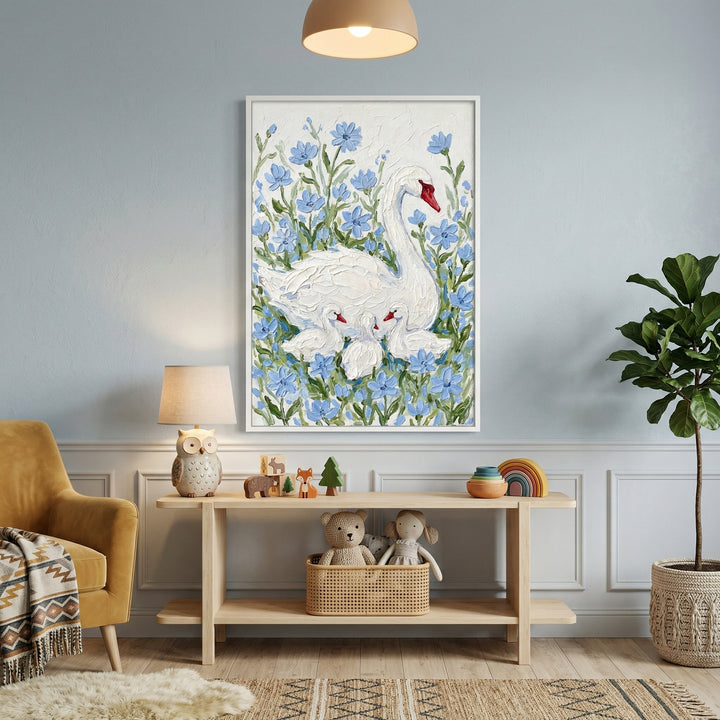 Framed painting of a white swan with three cygnets surrounded by soft blue flowers hangs above a wooden console table styled with toys and decor. A cozy nursery corner with a lamp armchair and plants creates a warm inviting space centered around the artwork.