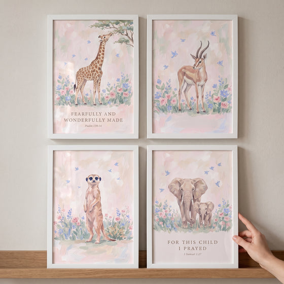 Blush botanical safari animals wall art set of 4 with a giraffe, gazelle, meerkat, and elephants in white frames.