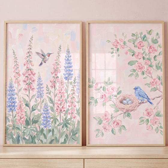 Blush pink garden bird wall art set of 2 showing a hummingbird among tall flowers and a bluebird beside a nest and roses.