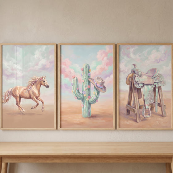 Blush pink western cowgirl wall art set of 3 featuring a running horse, cactus with a hat, and a saddle.