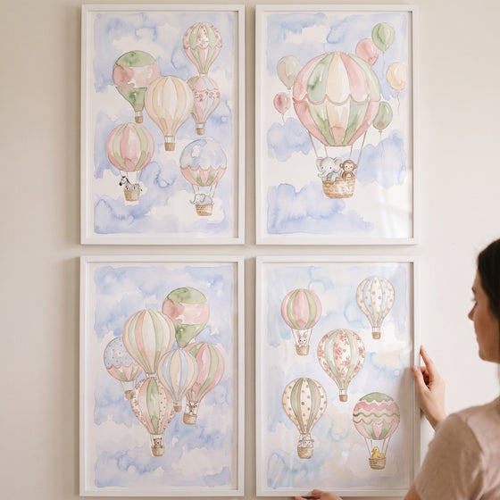Chic blush hot air balloon artwork set of 4 featuring soft pastel colors and cute animals displayed in frames on a wall.