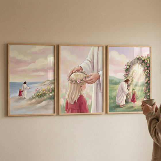 Three vertical wooden frames hang on a neutral wall, showcasing a series of tender illustrations. In the first, Jesus walks along a sandy shore with a young child in a red dress under a soft, pastel sky. The central piece captures a close-up of Jesus gently placing a crown of pink flowers on the blonde-haired girl's head. The final scene depicts them in a sunlit garden beside a stone archway covered in roses. The collection features a soft, illustrative aesthetic with a warm, peaceful palette.