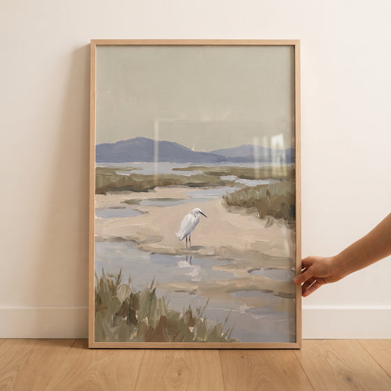 Framed coastal marsh snowy egret bird wall art showing a white bird in a wetland with grass and distant hills.