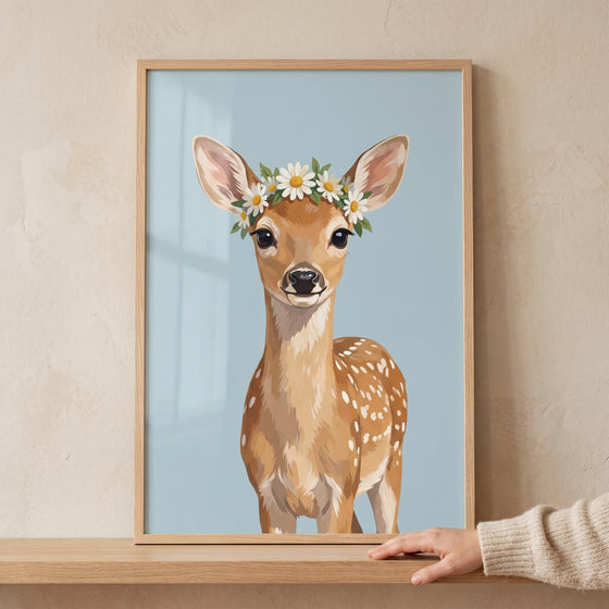 Daisy flower crown fawn wall art in a light wood frame featuring a spotted deer illustration on a pale blue background.