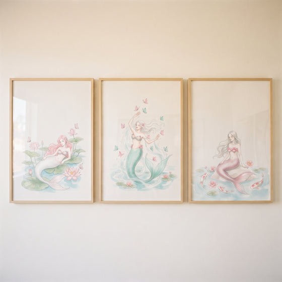 Delicate botanical watercolor mermaid wall art set of 3 with pastel mermaids among lotuses, butterflies, and koi fish.