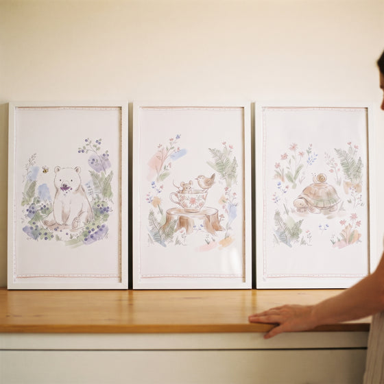 Dreamy botanical woodland animal wall art set of 3 featuring a bear, mouse, and turtle in white frames on a wooden table.