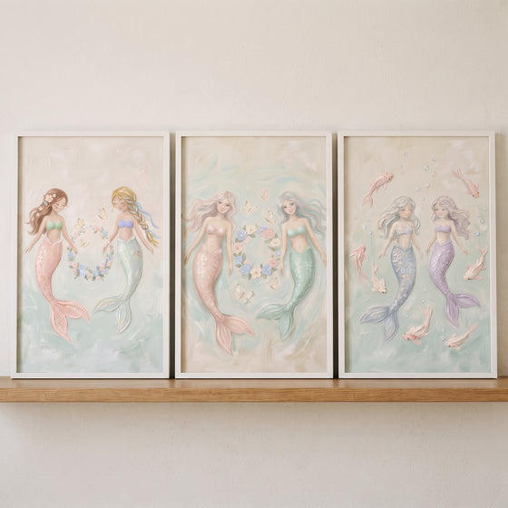 Dreamy textured sisters mermaid wall art set of 3 featuring soft pastel mermaids in white frames on a wooden shelf.