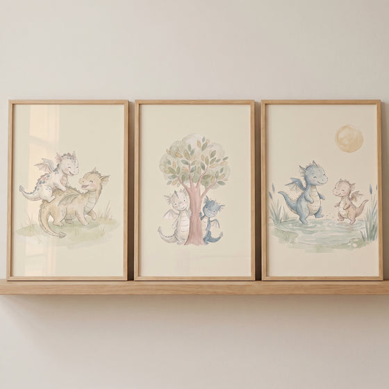 Earthy neutral baby dragon wall art set of 3 framed in wood on a shelf, showing soft illustrations of whimsical dragons.