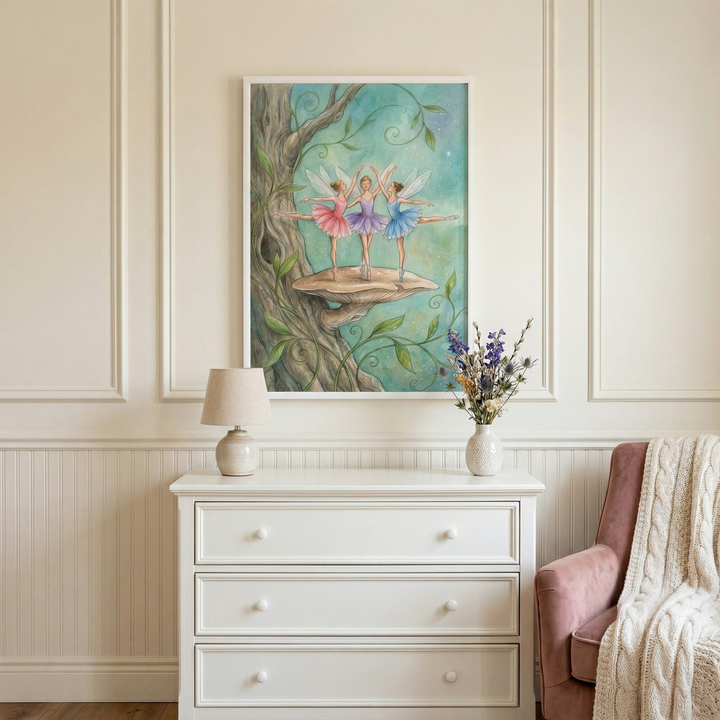 A framed piece of whimsical wall decor is displayed above a white three-drawer dresser in a serene, elegantly styled room. The central artwork depicts three winged figures in ballet attire, dancing on a large mushroom that extends from the side of a thick, textured tree trunk. Each figure wears a tutu in a different pastel shade—pink, lavender, and blue—and is captured in a graceful dance pose.