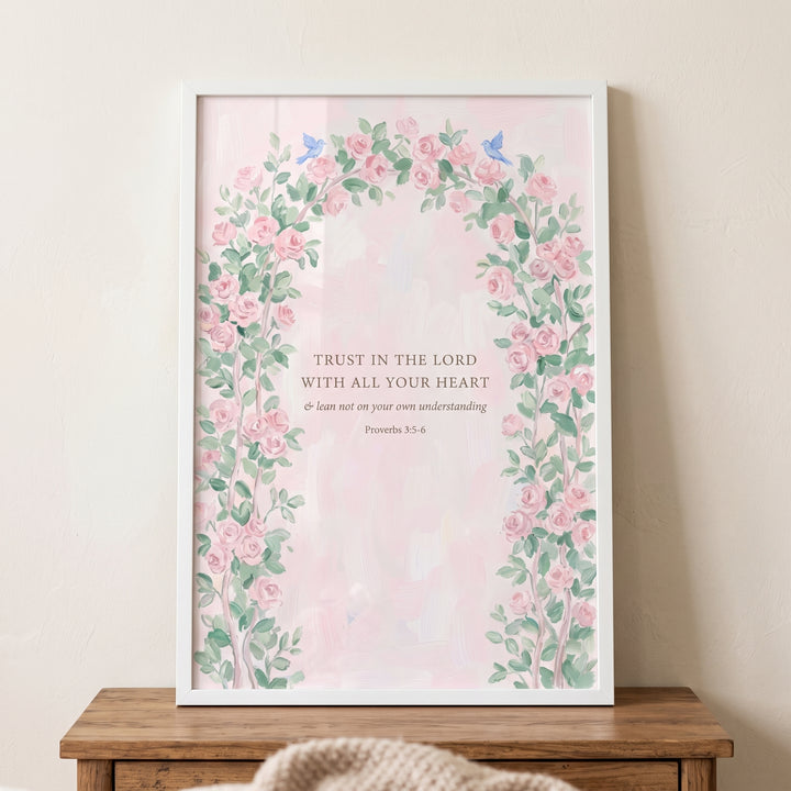 Floral arch proverbs verse bible wall art in a white frame with pink roses and small blue birds on a pink background.