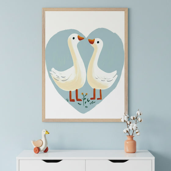 Modern kid's room with a light blue wall and white dresser. An illustrative framed print of two white geese forming a heart hangs centered above the dresser. A wooden goose toy and a vase with cotton sprigs sit on the dresser.