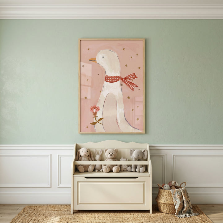 Cozy nursery with stuffed animals and woven decor beneath framed pink goose artwork featuring a white goose in a red scarf surrounded by gold stars.