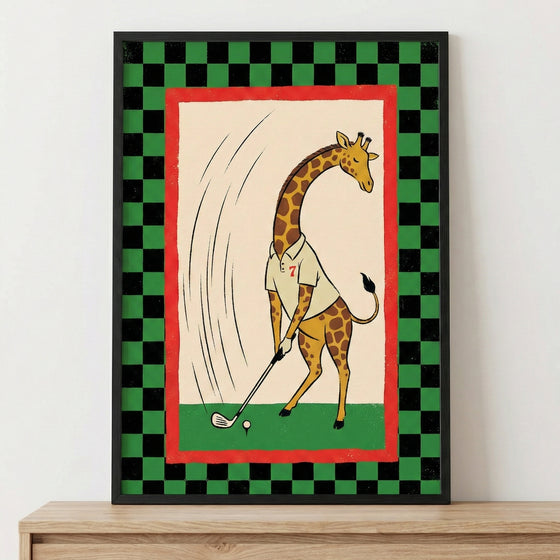 A framed illustration featuring a cartoon giraffe playing golf. The giraffe, depicted with its characteristic long neck and spots, is wearing a white collared shirt with a red number seven. It stands on green turf, holding a golf club and positioned to hit a white golf ball on a tee. Motion lines are drawn behind the giraffe to indicate a swing. This central scene is set on a cream-colored background with a red border, surrounded by a black and green checkered pattern.