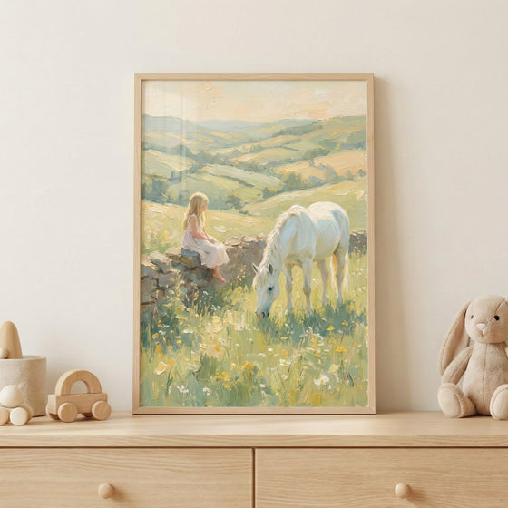 A framed pastel painting of a young girl in a light dress sitting on a stone wall while a white horse grazes in a sunlit wildflower meadow, displayed on a wooden dresser. Soft rolling hills stretch across the background in muted green and golden tones, and simple wooden toys and a plush bunny beside the frame create a calm, storybook inspired nursery setting.