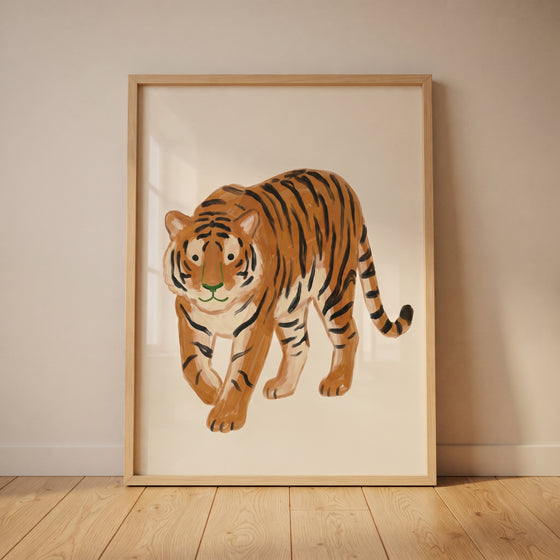 Green nose orange tiger wall art in a light wood frame leaning against a neutral wall on a wooden floor.