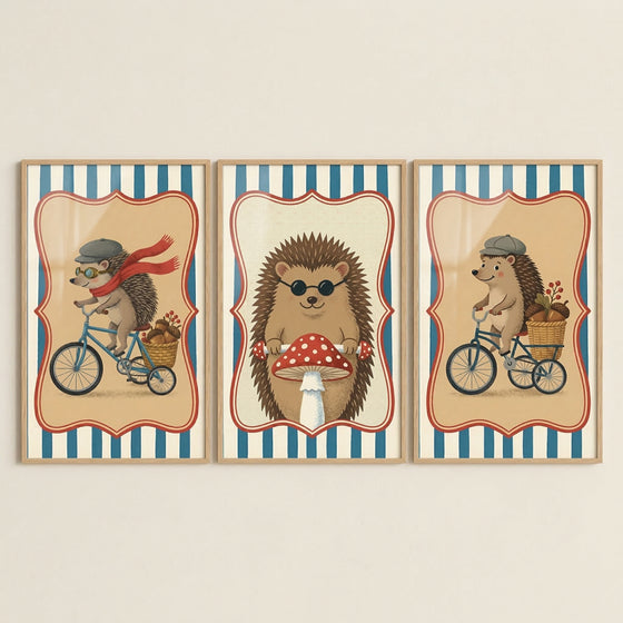 Three vertical framed art prints are displayed side-by-side, featuring whimsical illustrations of anthropomorphic hedgehogs in a retro style. Each print is enclosed in a light-colored wood frame.
The illustration on the left shows a hedgehog wearing a grey flat cap, goggles, and a long red scarf trailing behind as it rides a blue bicycle. A small basket filled with acorns is perched on the back of the bike.