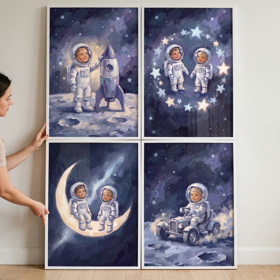 Person holds an inky sapphire baby astronaut wall art set of 4 featuring cosmic illustrations in white frames.