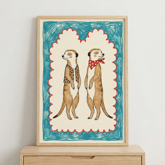 Framed illustration of two upright meerkats with closed eyes, one wearing a leopard-print vest and the other a red bandana with white stars, bordered by a playful red scallop and teal scribble background.