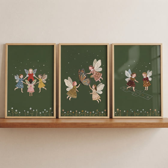 Moody forest floor fairies wall art set of 3 depicts fairies playing games on dark green backgrounds on a wooden shelf.