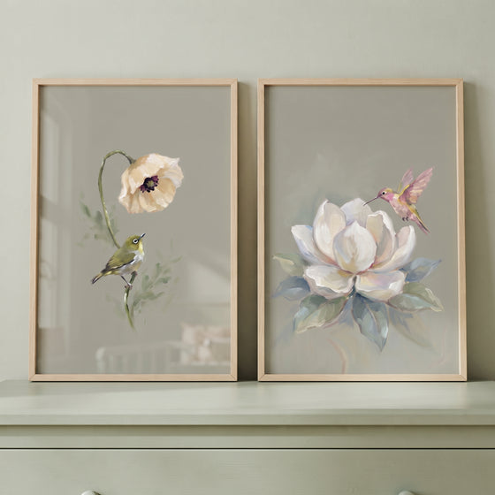 Muted olive garden bird wall art set of 2 shows a small bird and a hummingbird with large cream blossoms in wood frames.