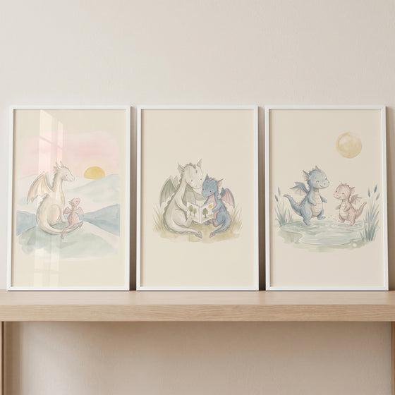 Muted wash baby dragons wall art set of 3 depicts cute dragons reading, playing near water, and watching a sunset.