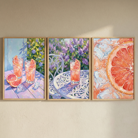 A triptych of framed wall art hangs on a neutral surface, capturing a sun-drenched garden setting. In the first piece, two glasses of pink citrus drink and ice cubes sit on a lavender table with fruit wedges. The middle work features a single glass on a white metal table surrounded by purple blossoms. The final piece provides a detailed close-up of a citrus slice and ice in a bubbly liquid. The style is textural and colorful, with an emphasis on light and shadow.