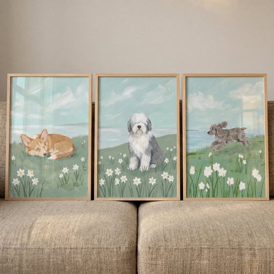 Ocean view meadow dogs wall art set of 3 features a corgi, sheepdog, and running dog in a field of white flowers.