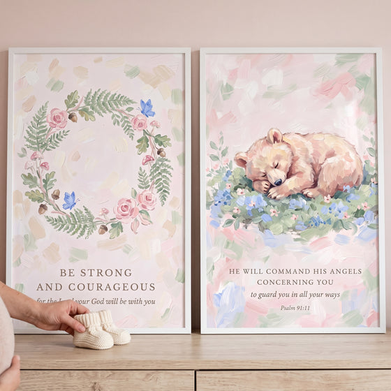 Painterly blush pink scripture bible wall art set of 2 featuring a floral wreath and a sleeping bear beside baby booties.