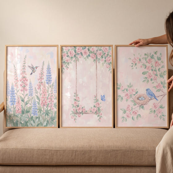 Painterly pink botanical garden wall art set of 3 with birds, flowers, and a swing resting on a beige sofa.
