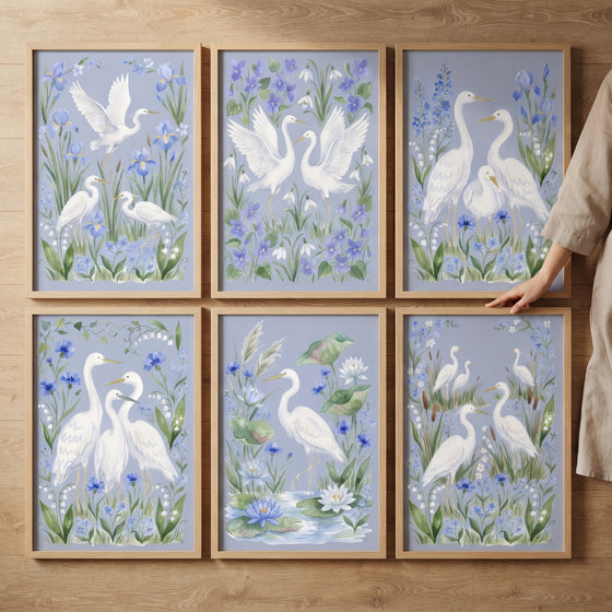 Six wood-framed prints form this pastel coastal wading bird wall art set of 6, featuring white herons and blue flowers.