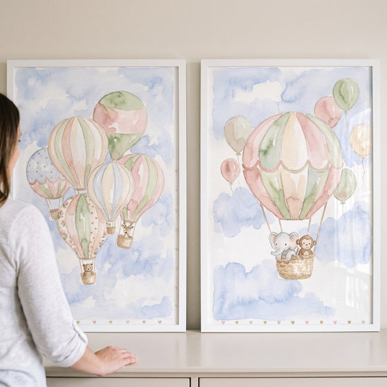 Pastel hot air balloon wall art set of 2 featuring watercolor baby animals floating in baskets through blue clouds.