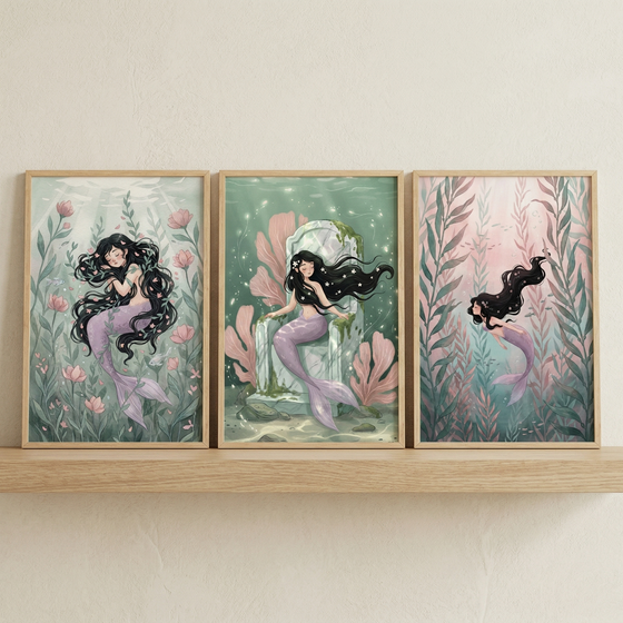Three framed illustrations of a mermaid are displayed on a light wood shelf. Each artwork depicts the same character with long, wavy black hair and a lavender tail in different underwater scenes. On the left, she is curled in a peaceful sleep amidst soft green foliage and pink blossoms. In the middle, she sits on a stone throne surrounded by glowing particles and pink coral. On the right, she swims upwards through tall sea plants towards a warm, pink-hued light. The art style is whimsical and delicate.