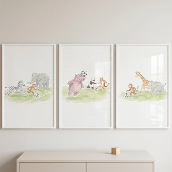 Playful soccer safari animals wall art set of 3 featuring watercolor wild animals playing on a grassy field.