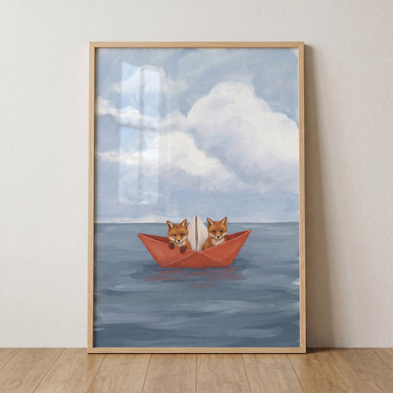 Two small foxes in a red paper boat foxes wall art, floating on blue water beneath a soft cloudy sky.