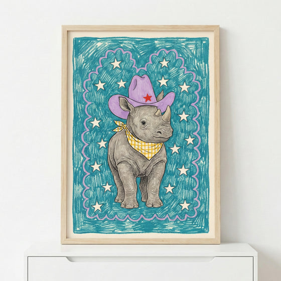 Framed illustration of a baby rhino wearing a purple cowboy hat with a red star and a yellow checkered bandana, standing against a teal background with white stars. The playful, hand-drawn style makes it perfect for nursery or toddler room decor.