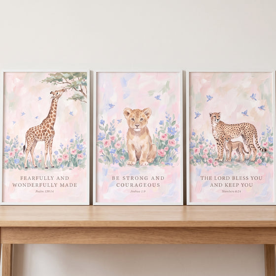 Scripture blush wildflower animals wall art set of 3 with a giraffe, lion cub, and cheetah on a wooden shelf.