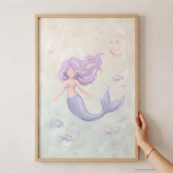 Serene swimming pastel mermaid wall art with lavender hair and colorful fish in a light wood frame.