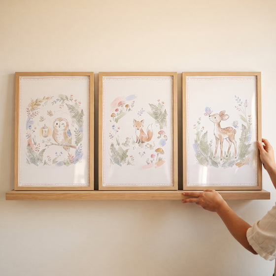 Serene watercolor forest animal print set of 3 featuring an owl, fox, and deer in wooden frames on a wall shelf.