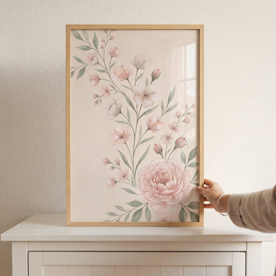 Shabby chic floral wall art with pink blossoms and green leaves in a light wood frame on a white cabinet.