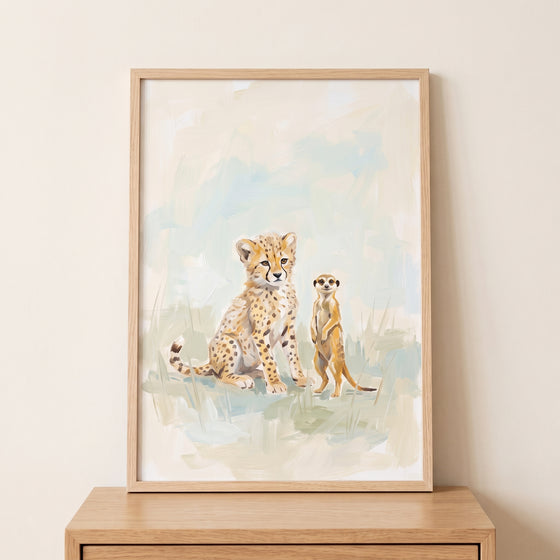 Framed sitting spotted cheetah meerkat animals wall art resting on a wooden surface against a neutral wall.