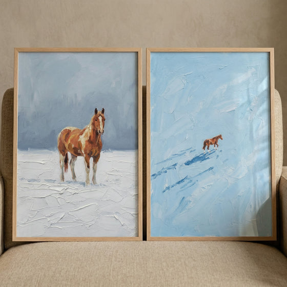 Two framed textured paintings of horses in a snowy landscape, one showing a single brown horse standing in a soft white field and the other showing a small distant horse walking across a pale blue snowy scene. The minimal composition and cool tones create a quiet peaceful winter atmosphere.